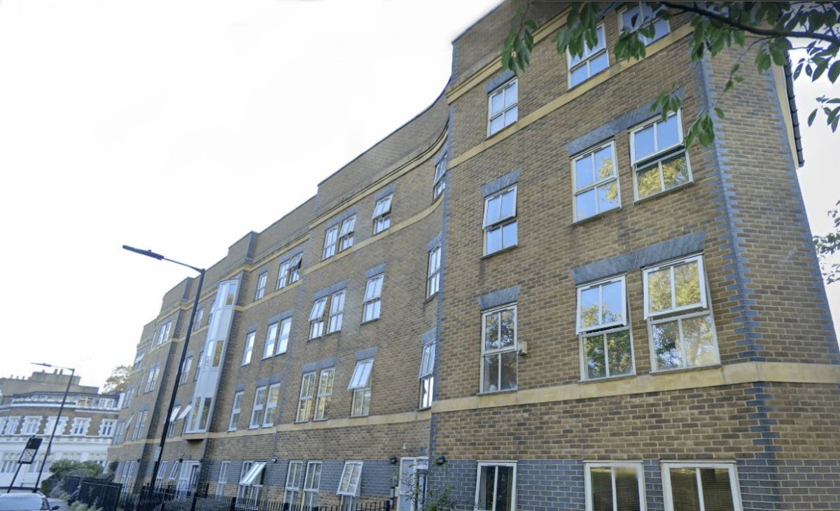A modern brick apartment building in Cadogan Terrace with multiple timber casement windows, bathed in sunlight, amidst an urban setting with green trees.